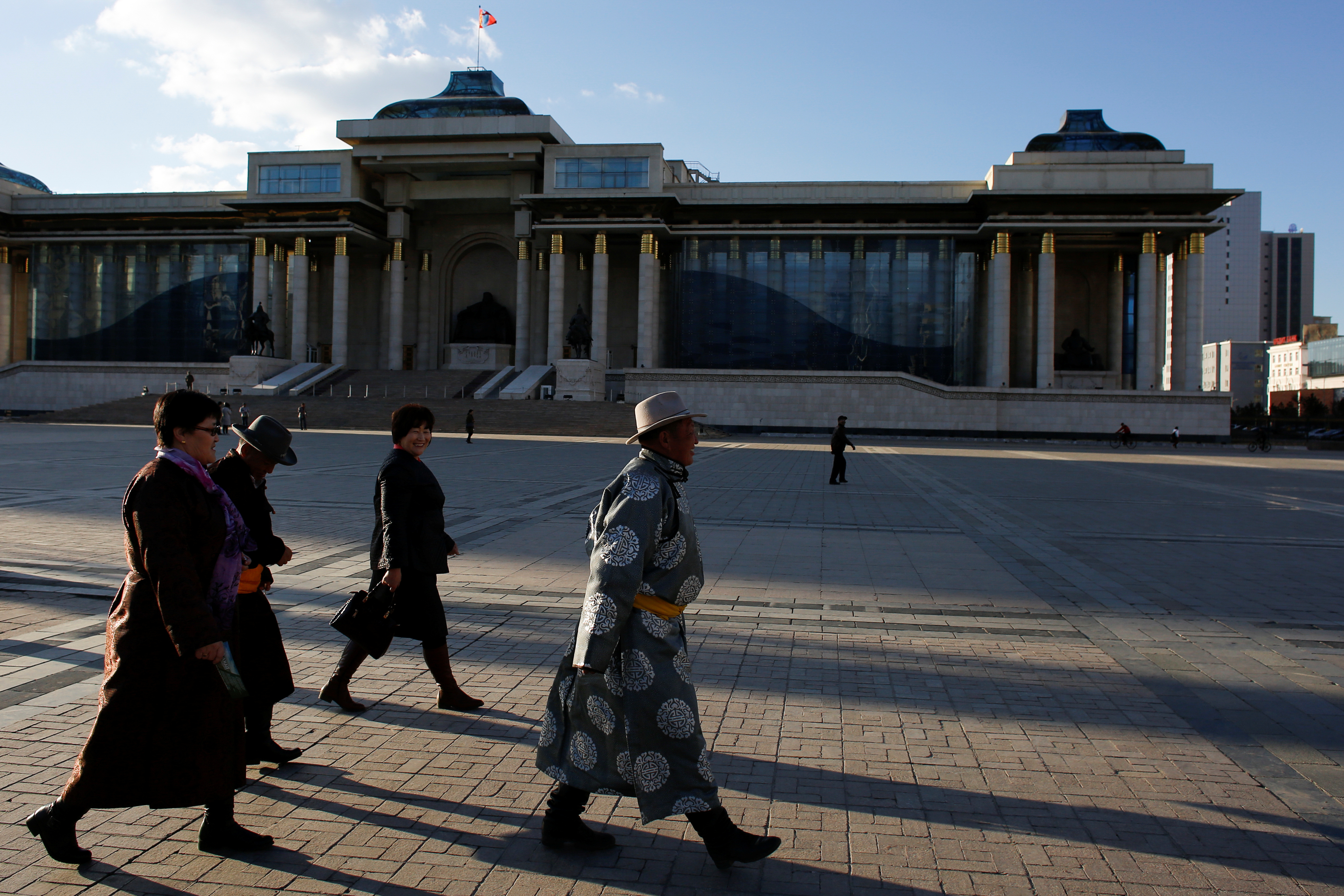 People in traditional clothes walk past the parliament building in Sukhbaatar square in Ulaanbaatar