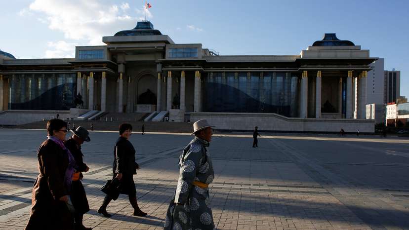 People in traditional clothes walk past the parliament building in Sukhbaatar square in Ulaanbaatar