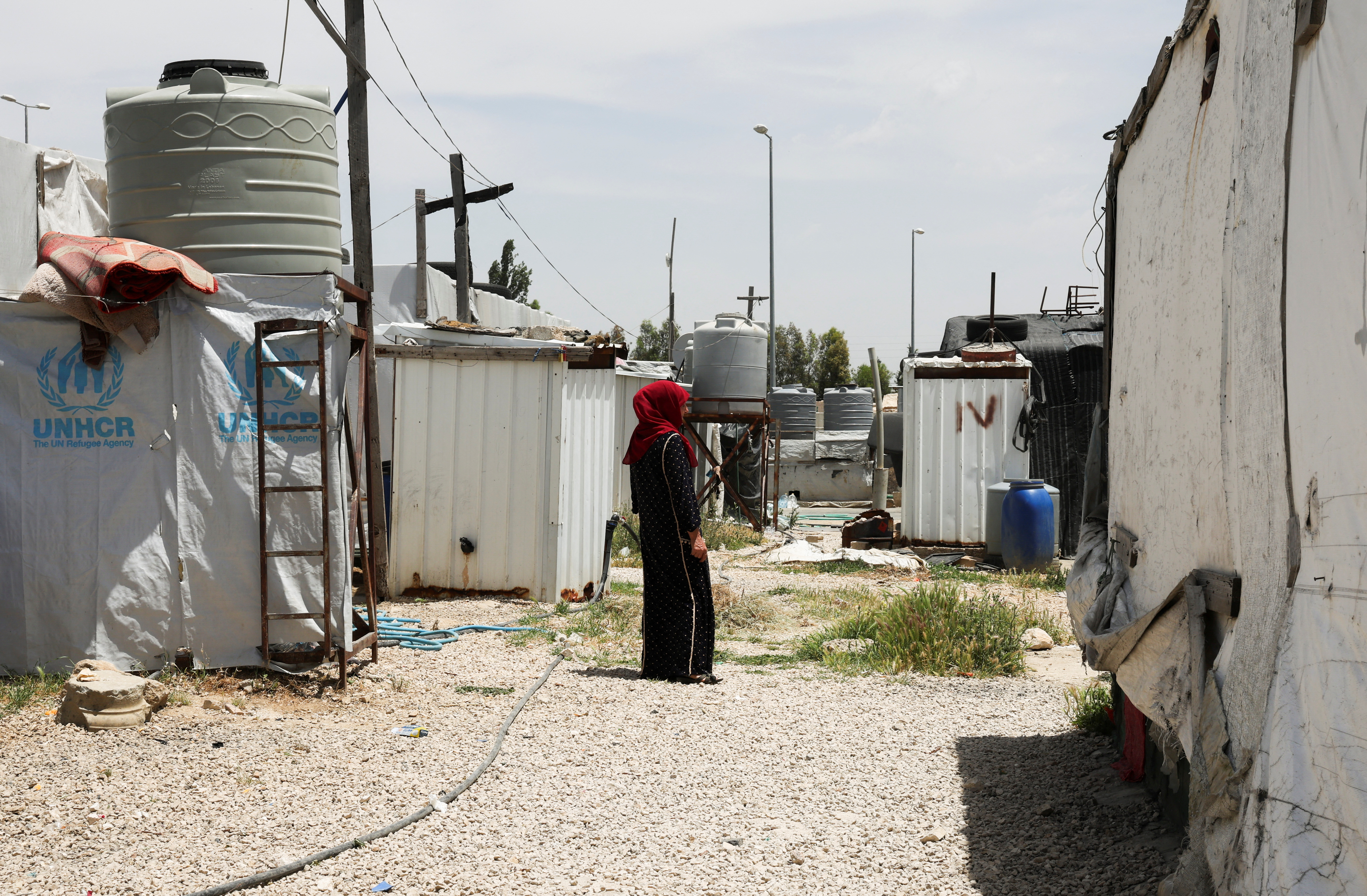 A Syrian refugee woman stands near tents at an informal tented settlement in the Bekaa valley