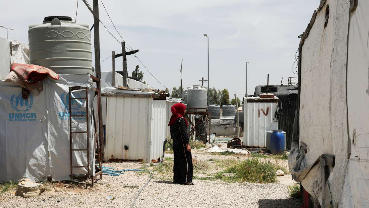 A Syrian refugee woman stands near tents at an informal tented settlement in the Bekaa valley