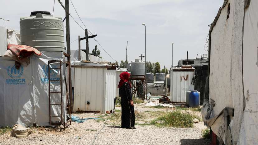 A Syrian refugee woman stands near tents at an informal tented settlement in the Bekaa valley