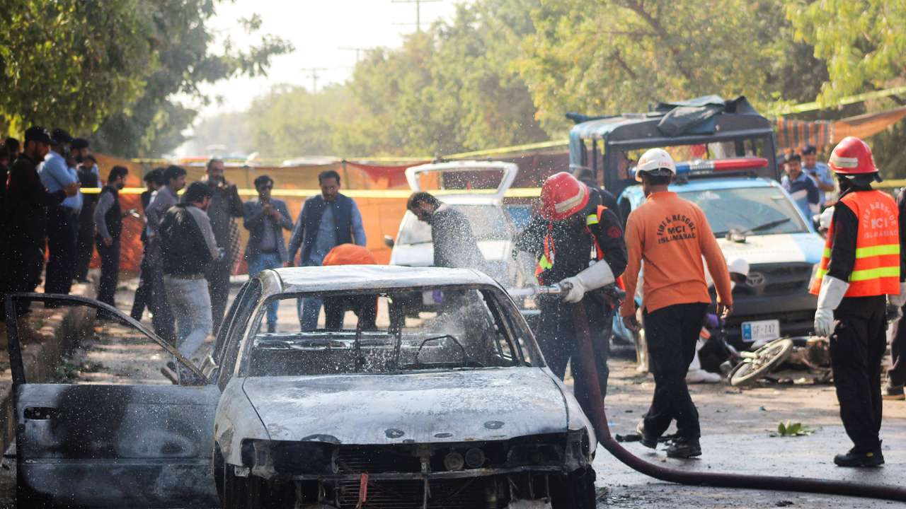 Firefighter douses a vehicle after a blast outside a court building in Islamabad