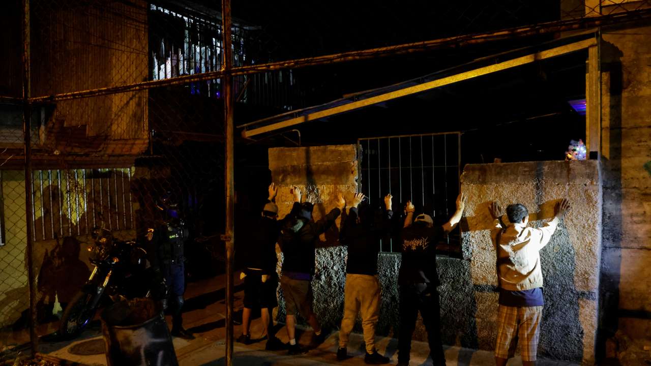 A police officer stands next to men briefly detained to frisk them for drugs and weapons during the "Costa Rica Segura Plus" operation, in San Jose