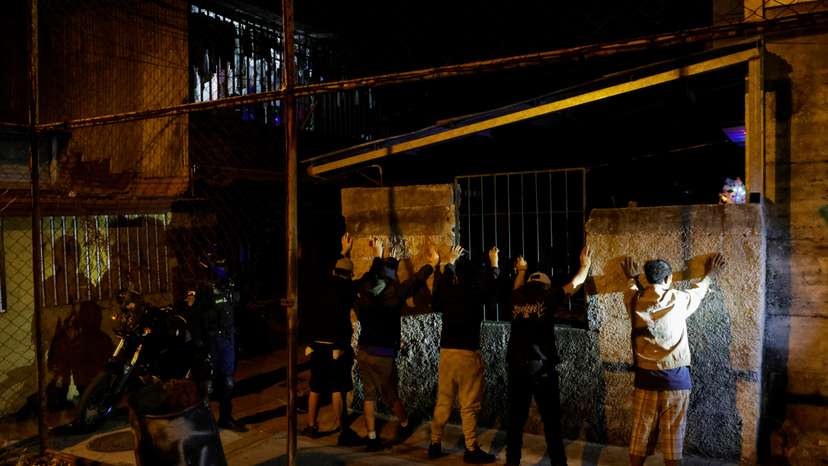 A police officer stands next to men briefly detained to frisk them for drugs and weapons during the "Costa Rica Segura Plus" operation, in San Jose