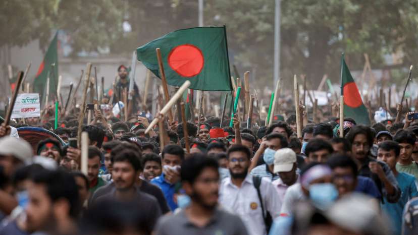 Anti-quota protesters march with Bangladeshi flags and sticks as they engage in a clash with Bangladesh Chhatra League, the student wing of the ruling party Bangladesh Awami League, at the University of Dhaka
