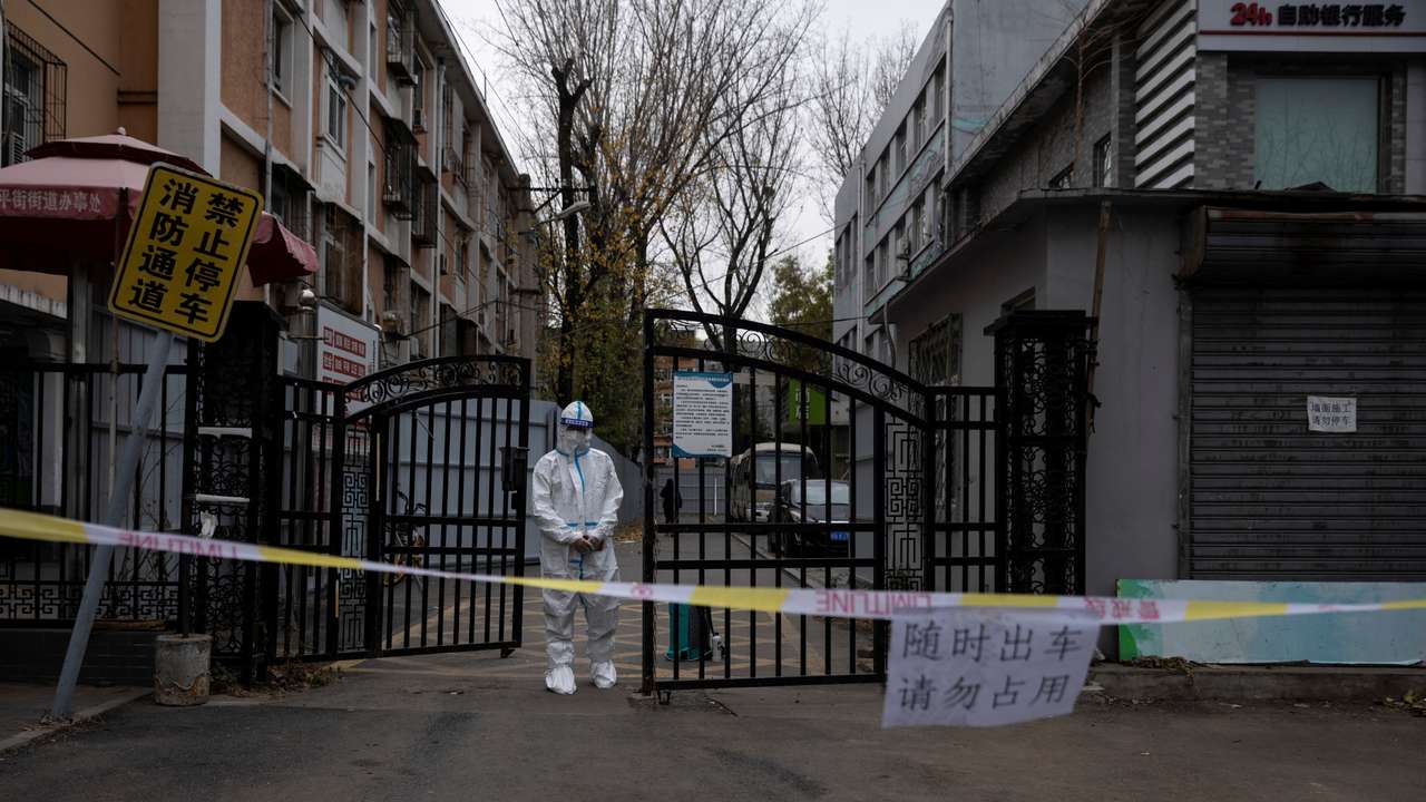 An epidemic-prevention worker in a protective suit stands guard at the gate of a residential compound as coronavirus disease (COVID-19) outbreaks continue in Beijing