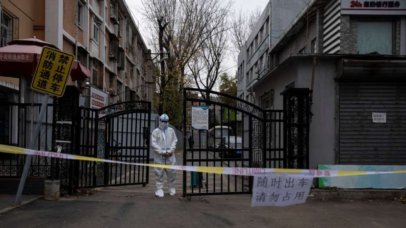 An epidemic-prevention worker in a protective suit stands guard at the gate of a residential compound as coronavirus disease (COVID-19) outbreaks continue in Beijing