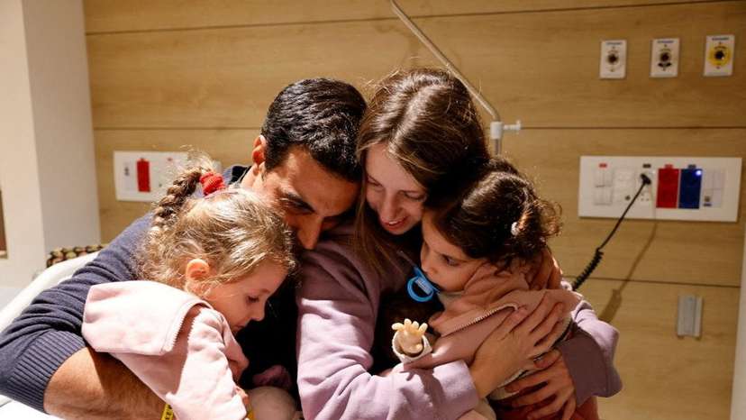 Aviv Asher, 2,5-year-old, her sister Raz Asher, 4,5-year-old, and mother Doron, react as they meet with Yoni, Raz and Aviv's father and Doron's husband, after they returned to Israel