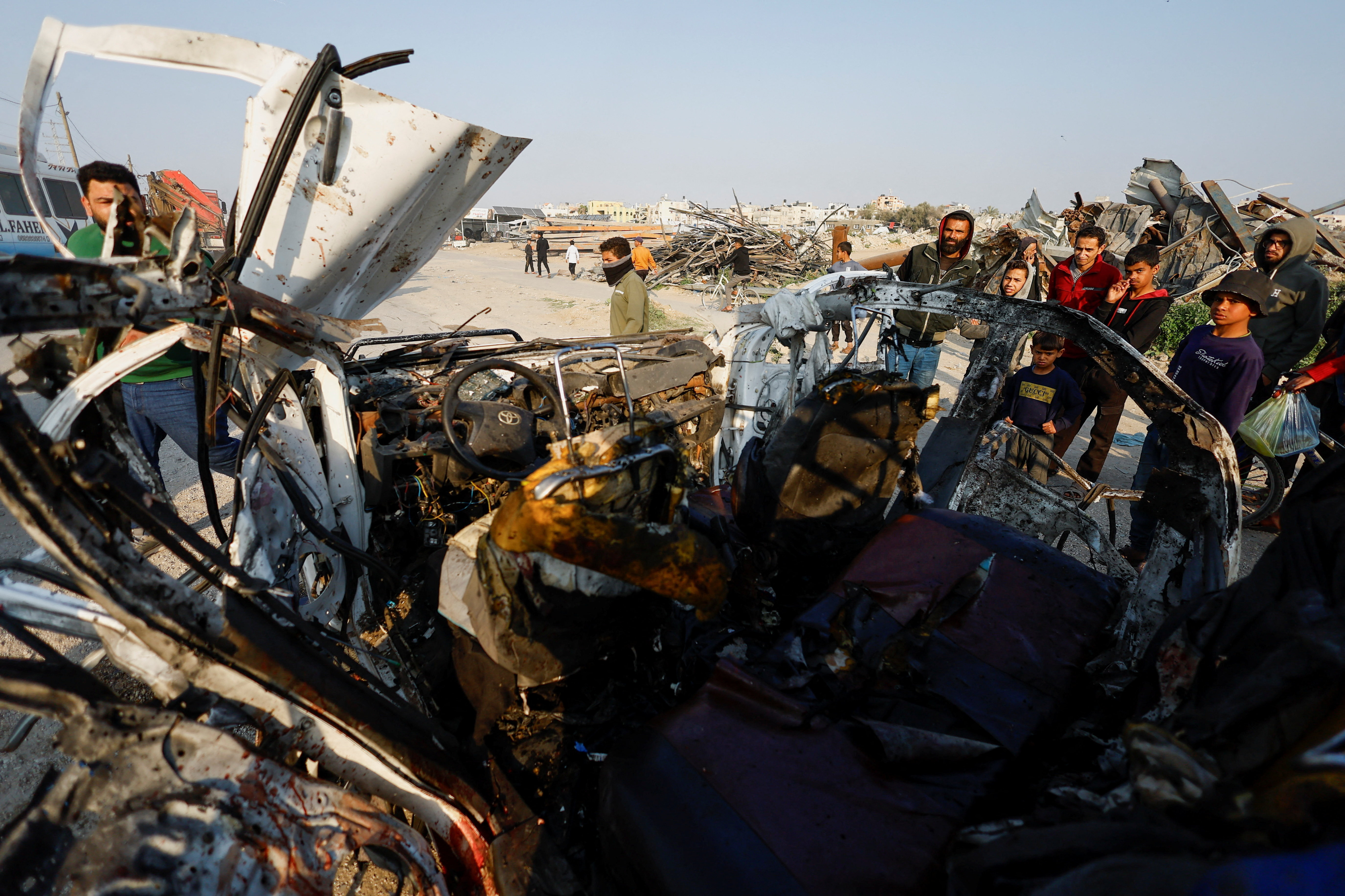 Palestinians inspect the site of an Israeli airstrike targeting a police vehicle in the central Gaza Strip
