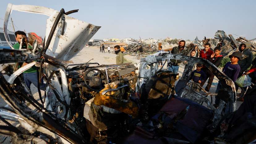 Palestinians inspect the site of an Israeli airstrike targeting a police vehicle in the central Gaza Strip