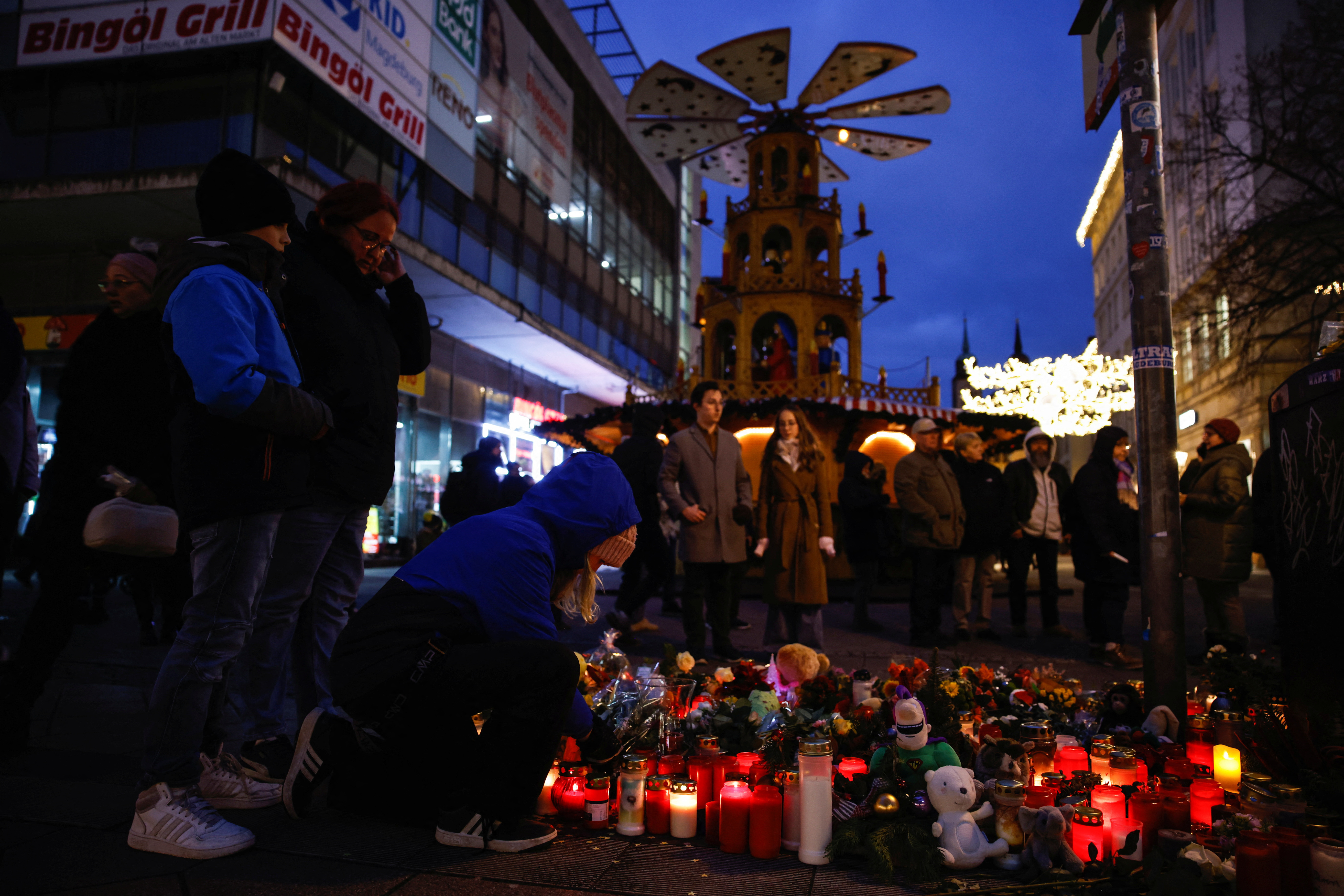 People look at flowers and candles left as a tribute for the victims of the 'Alter Markt' Christmas market, in Magdeburg