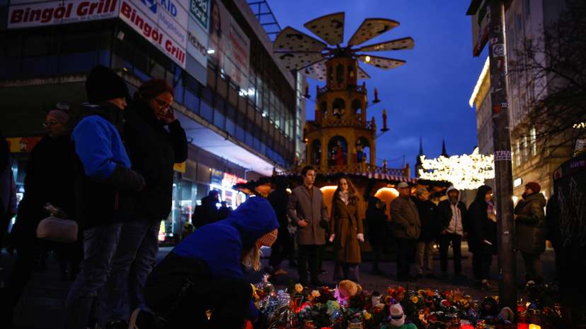 People look at flowers and candles left as a tribute for the victims of the 'Alter Markt' Christmas market, in Magdeburg