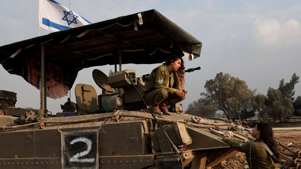 An Israeli soldier crouches on an armoured personnel carrier near the Israel-Gaza border