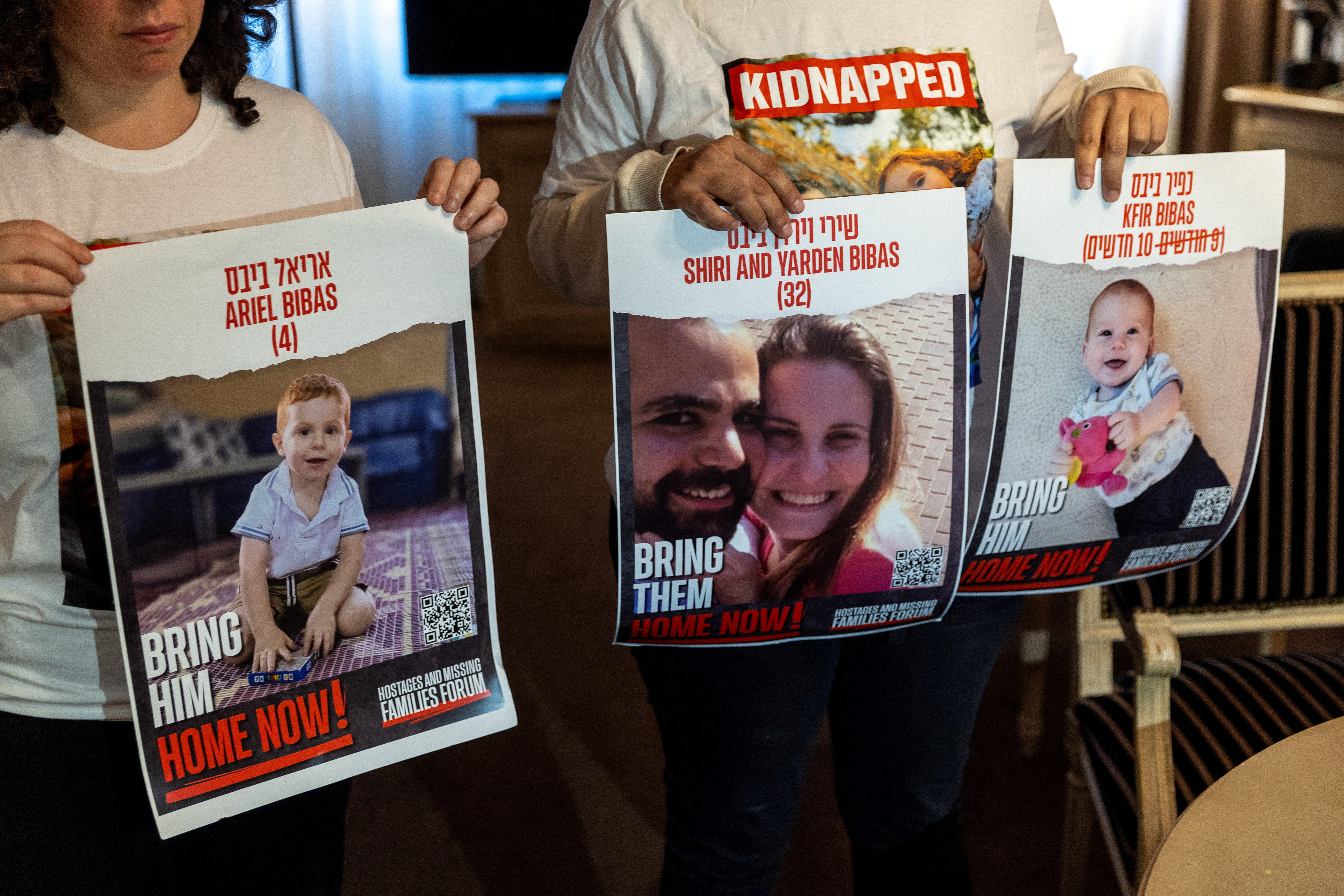 FILE PHOTO: Bibas Levy holds with her friend Ulus pictures of her brother Yarden who was kidnapped with his wife and 2 children in Geneva
