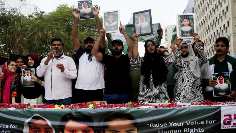 People carry pictures of the children who were killed after a suicide bomber struck an army school bus in Khuzdar district, as they gather in their memory, in Karachi