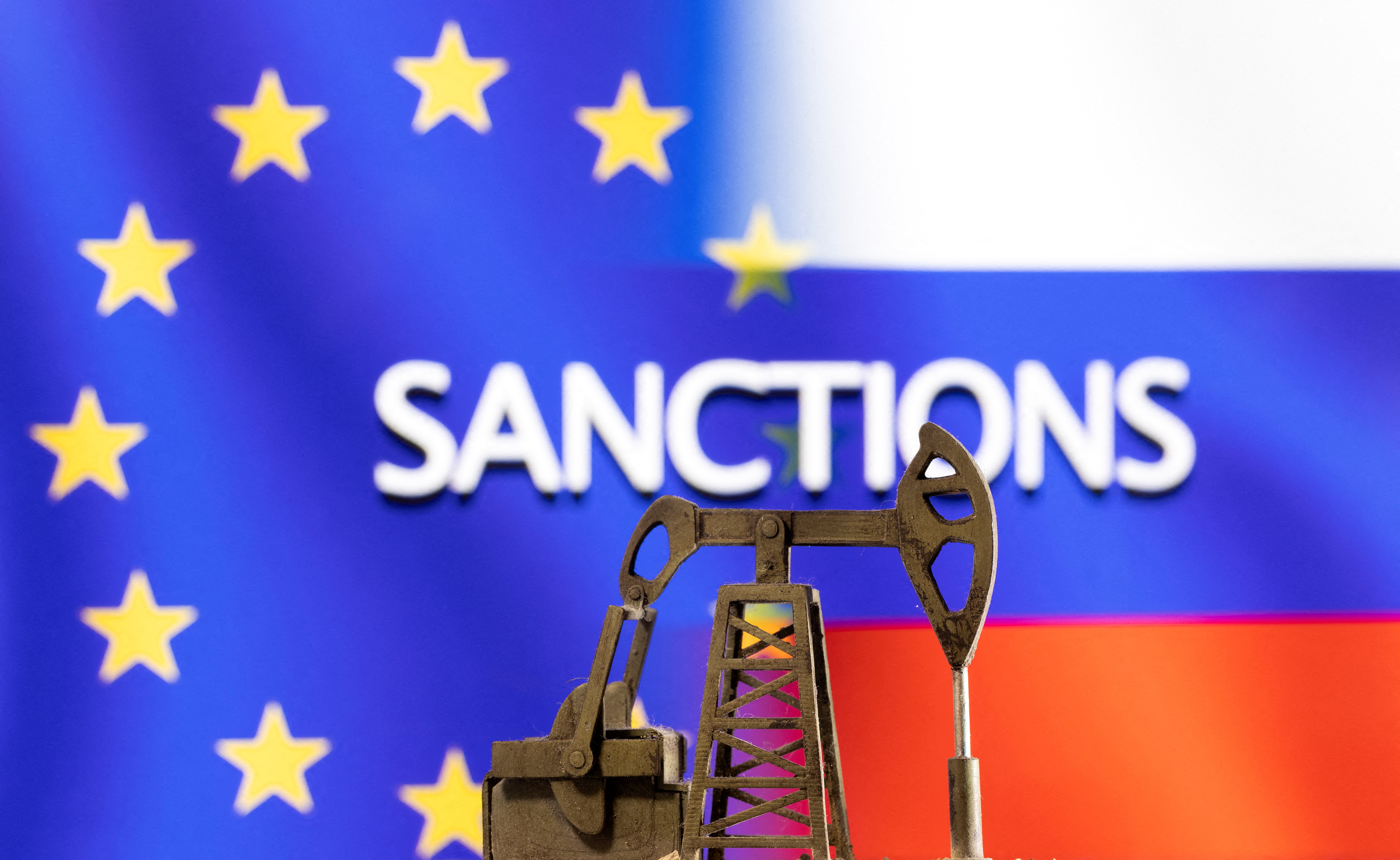 Illustration shows pump jack in front of the word "Sanctions", EU and Russia flag colours