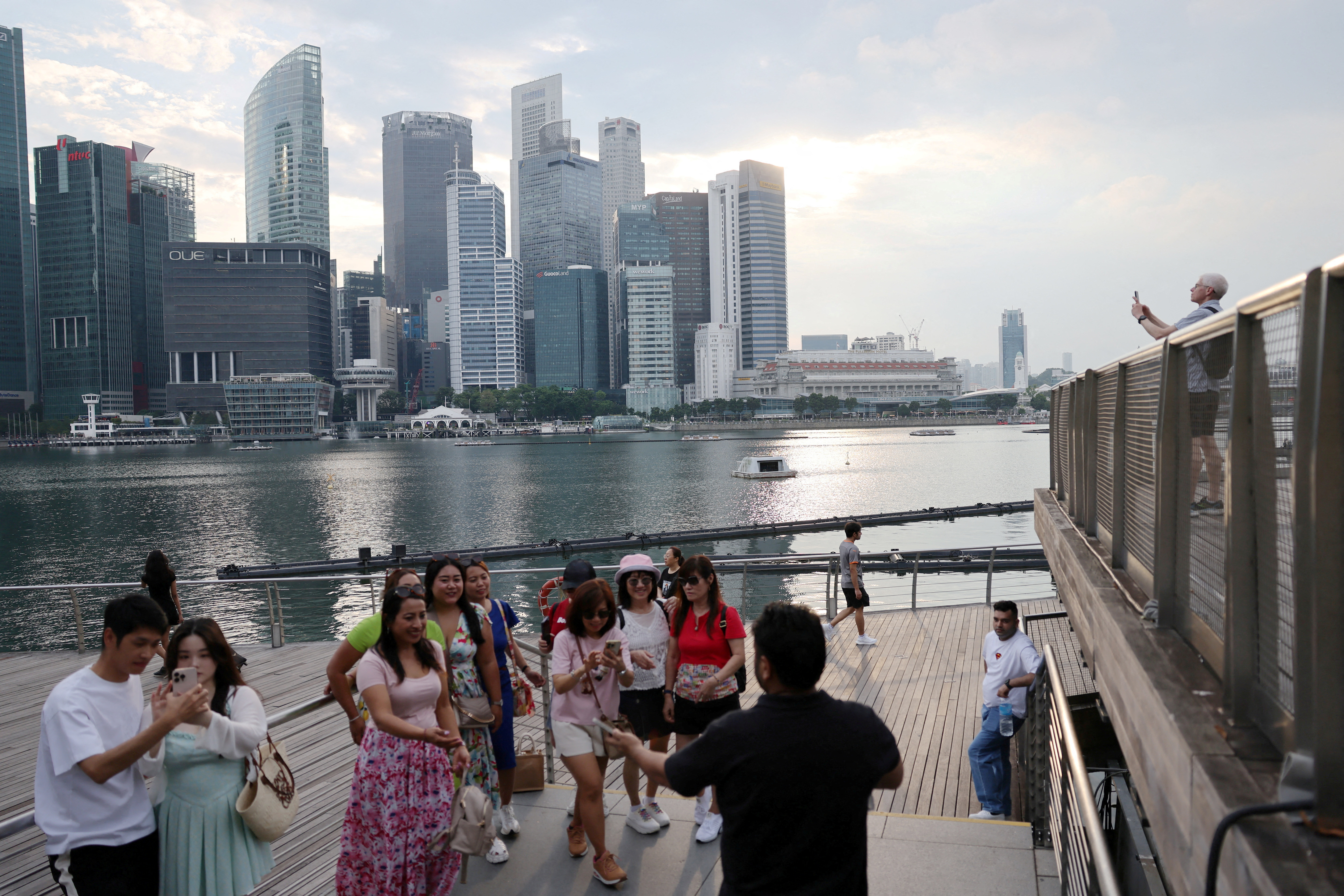 FILE PHOTO: People take photos of the central business district skyline in Singapore