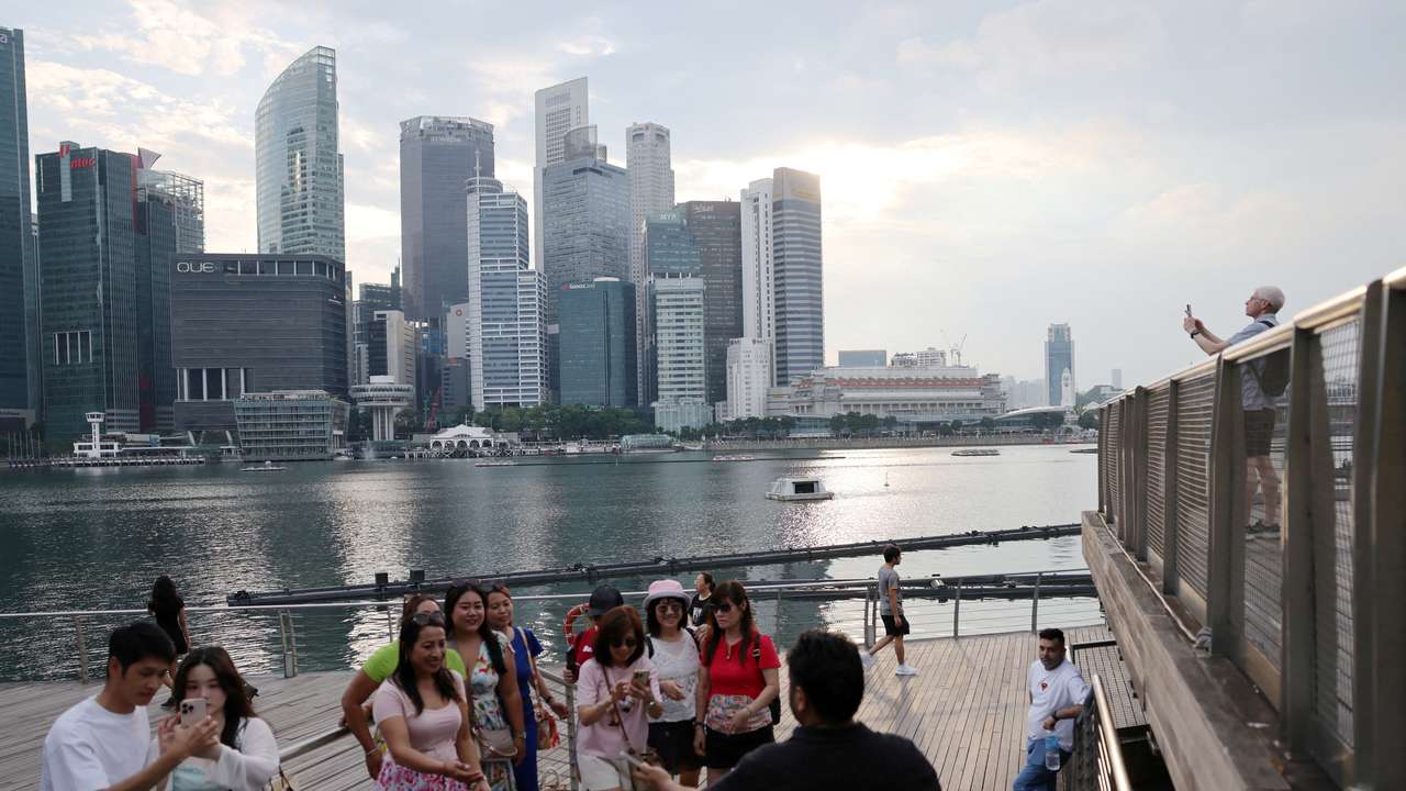 FILE PHOTO: People take photos of the central business district skyline in Singapore
