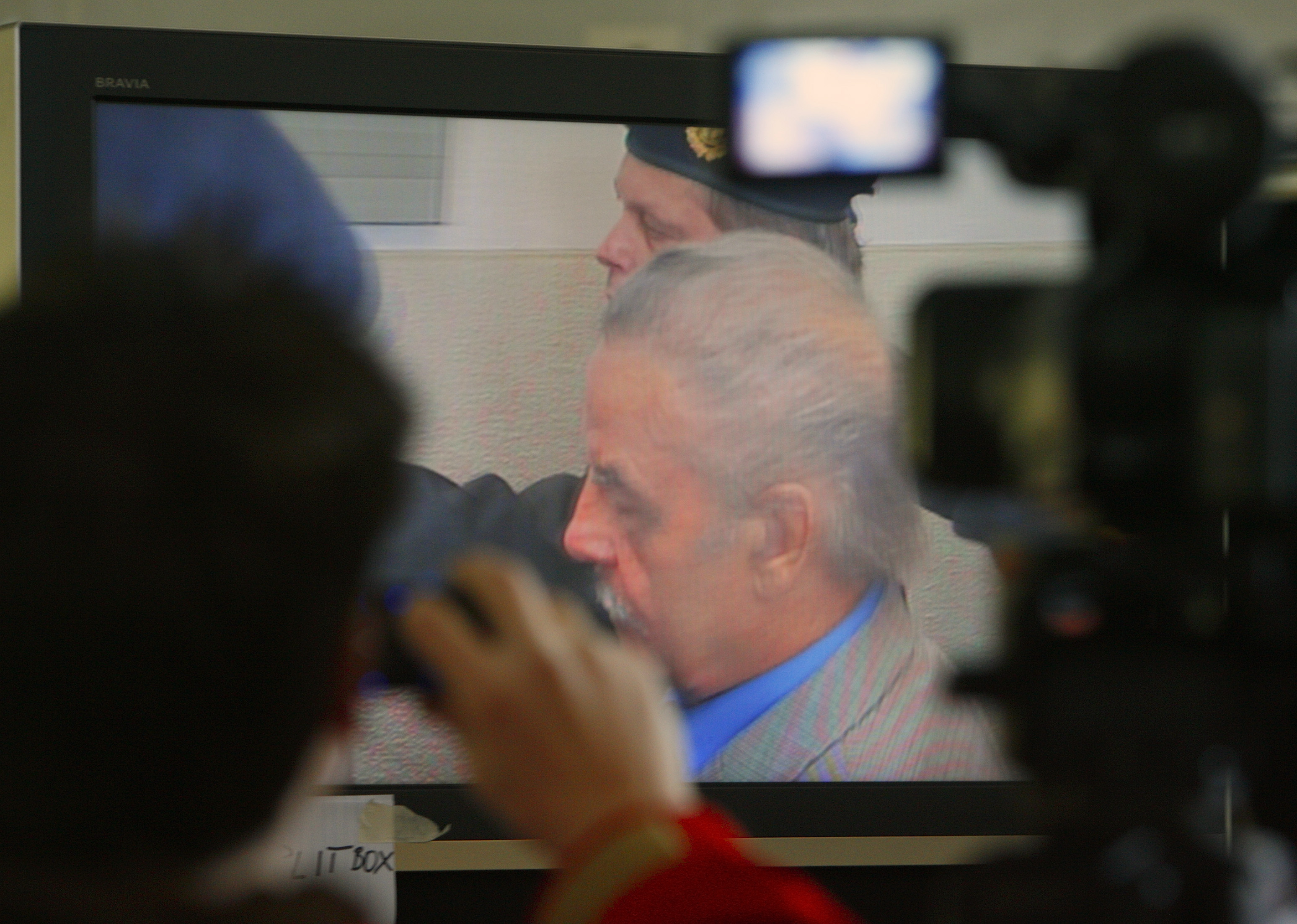 Journalists watch TV screen inside media tent as 73-year-old Austrian Fritzl appears in court on fourth day of his trial in St. Poelten