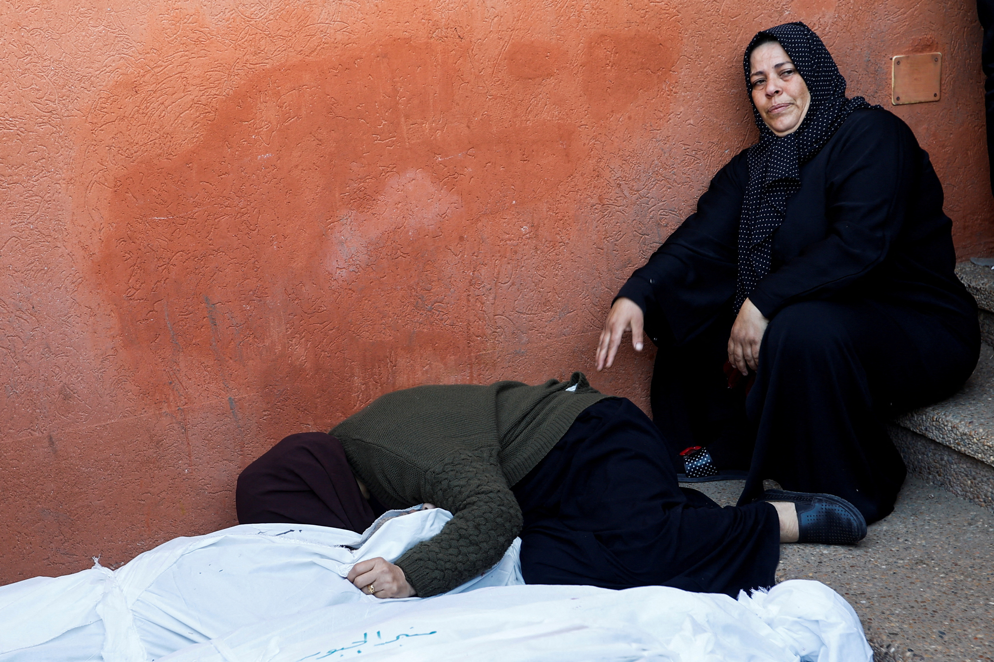 People mourn next to the bodies of Palestinians killed in Israeli strikes, during a funeral at Nasser hospital in Khan Younis