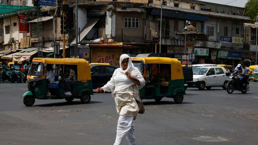 A woman covered with a cloth to protect herself from the heat walks on a road during a heatwave in Ahmedabad