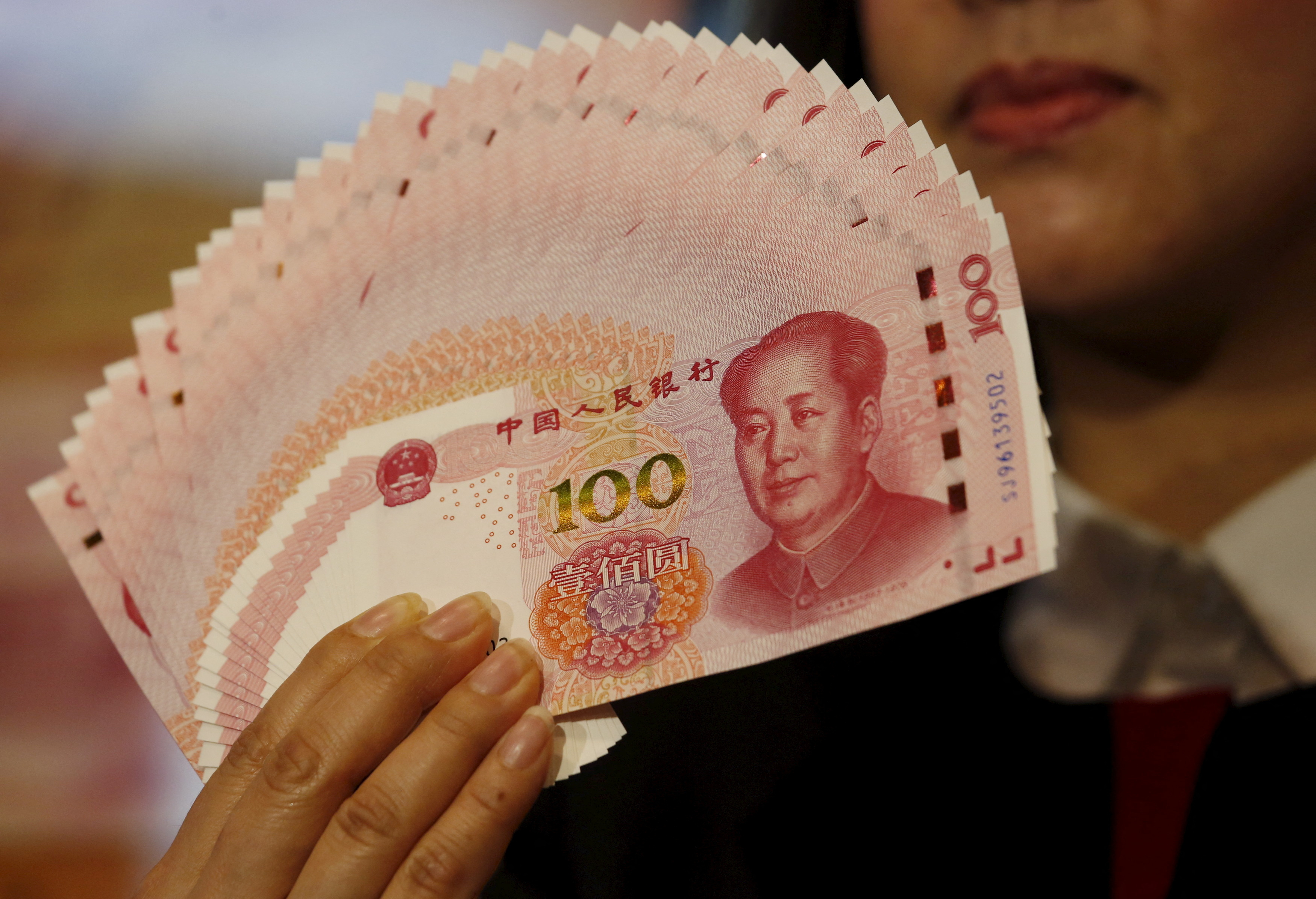 FILE PHOTO: A staffer poses with 2015 edition of the 100 renminbi notes at the Bank of China Tower in Hong Kong