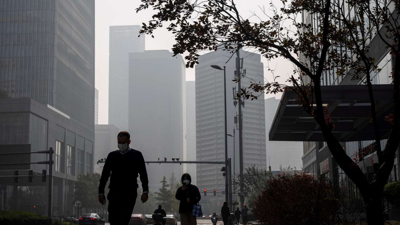 People walk in the Central Business District (CBD) on a hazy morning in Beijing