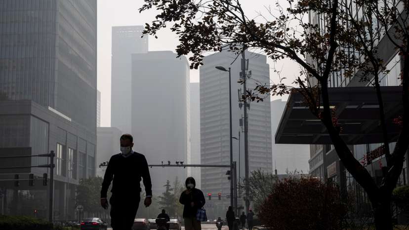 People walk in the Central Business District (CBD) on a hazy morning in Beijing