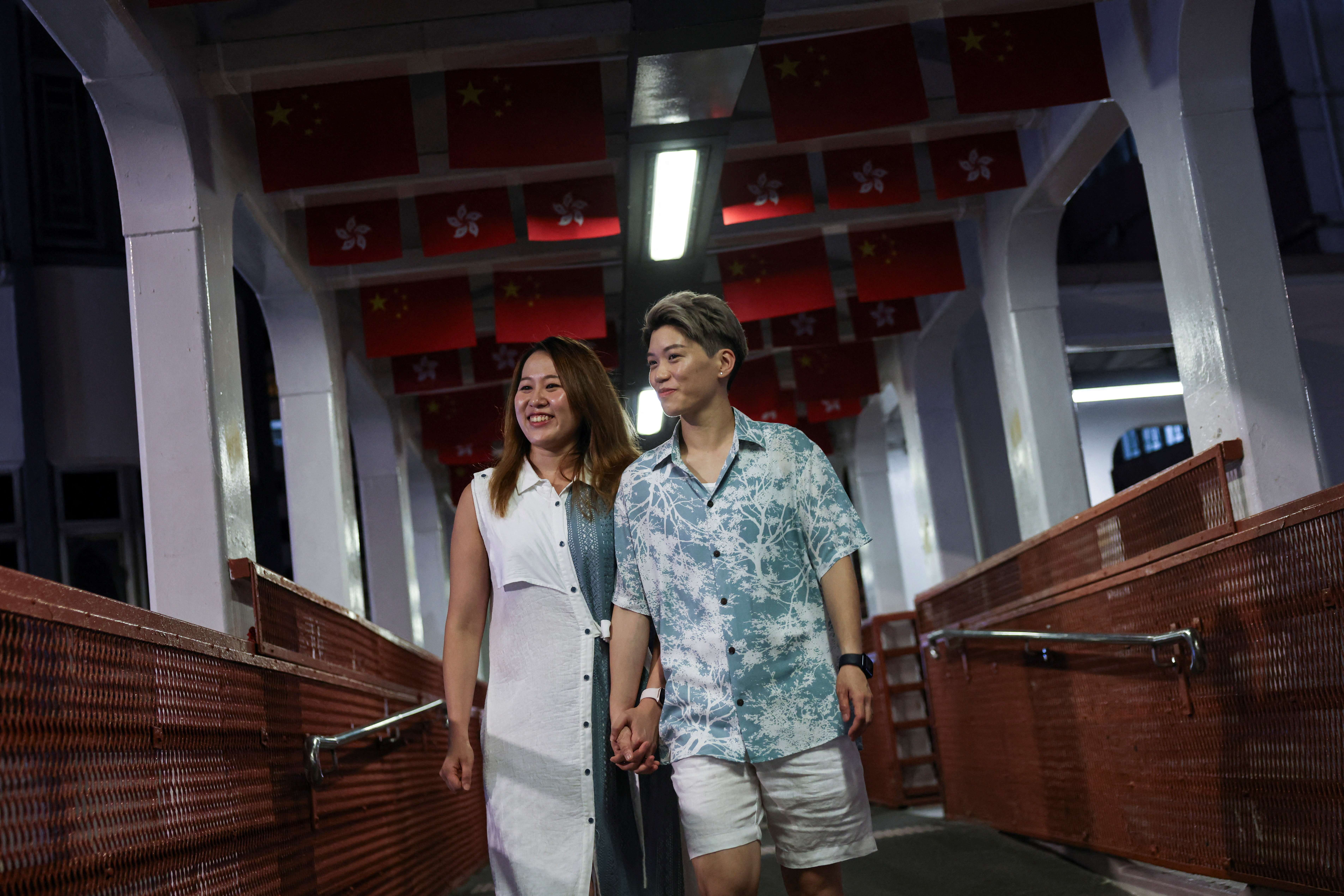 Gloria Tsang, a speech therapist, and her wife Jaedyn Yu, a drum school owner, walk on a pedestrian overpass in Hong Kong