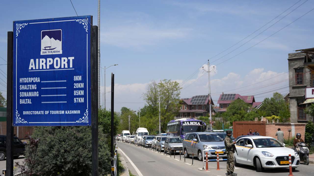 An Indian security force trooper keeps guard next to vehicles carrying travellers including tourists outside the airport in Srinagar
