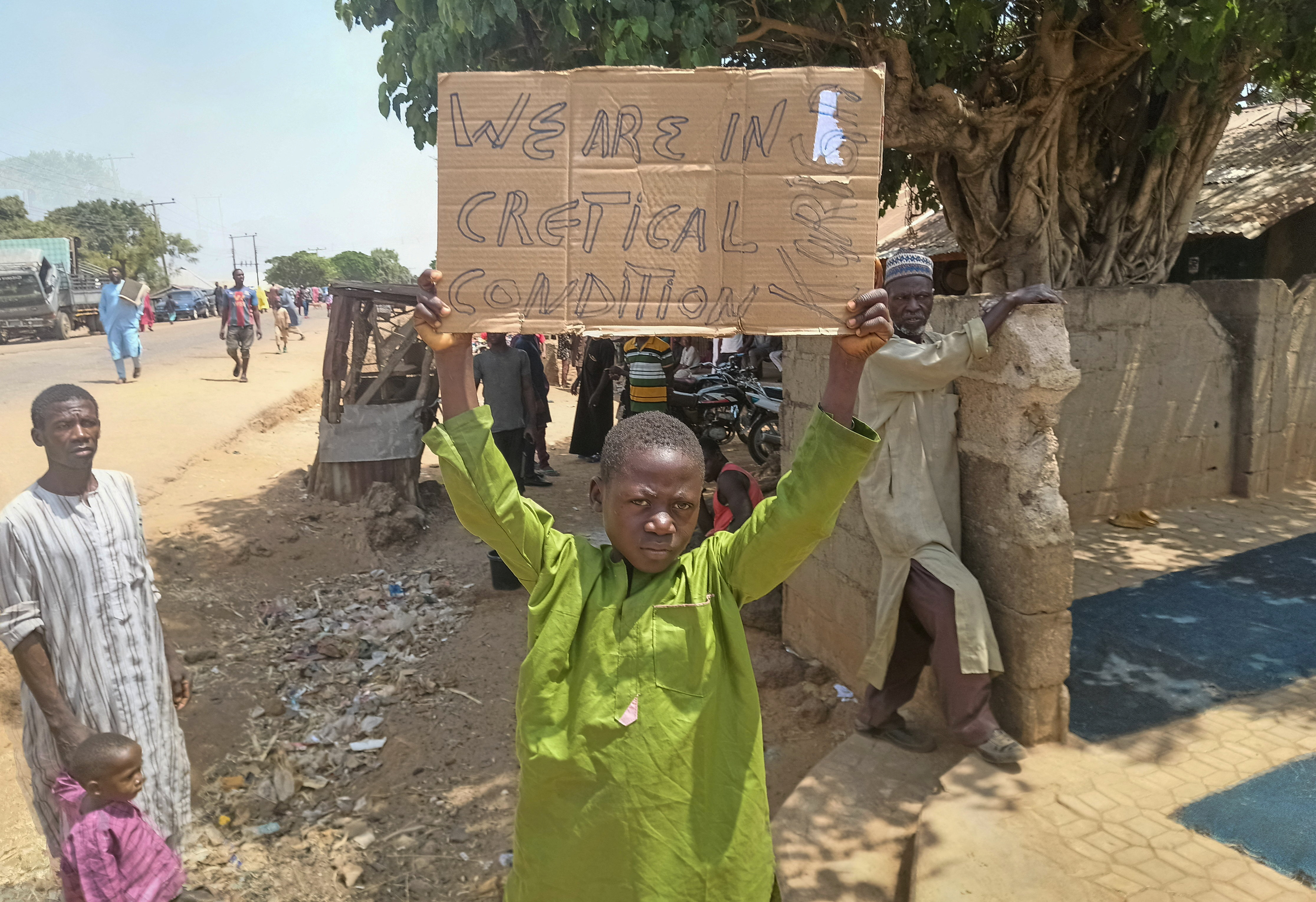 A boy holds a sign to protest against, what a teacher, local councilor and parents said, the kidnapping of hundreds school pupils by gunmen after the Friday prayer, in Kaduna