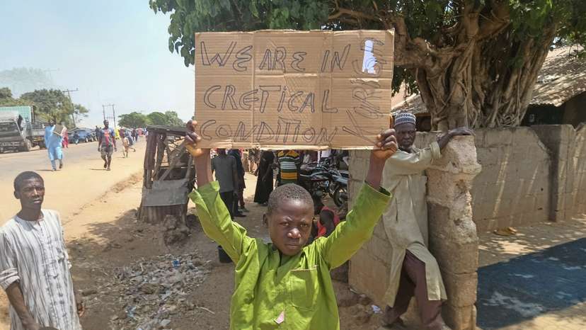 A boy holds a sign to protest against, what a teacher, local councilor and parents said, the kidnapping of hundreds school pupils by gunmen after the Friday prayer, in Kaduna