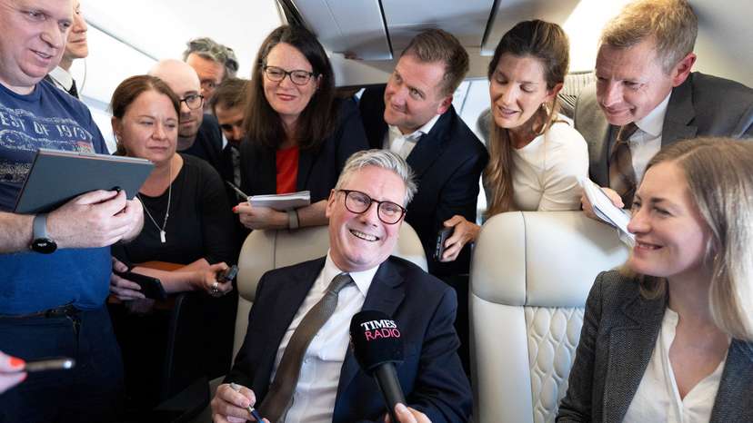 Britain's Prime Minister Sir Keir Starmer talks to journalists as he travels onboard a plane to Washington DC