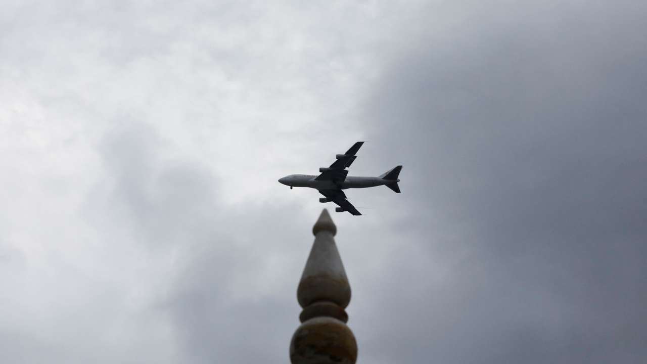 FILE PHOTO: A plane flies past a monumemt with the rain clouds in the background, during the monsoon season in Karachi