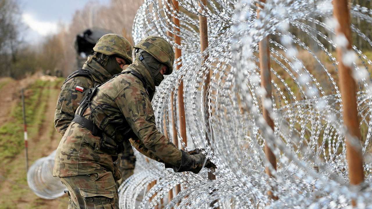 FILE PHOTO: Soldiers build razor wire fence on Poland's border with Russia's exclave of Kaliningrad near Bolcie