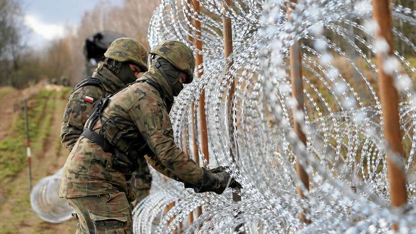 FILE PHOTO: Soldiers build razor wire fence on Poland's border with Russia's exclave of Kaliningrad near Bolcie