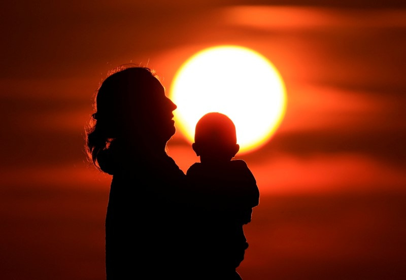 A mother and her baby enjoy the sunset on the beach in Calais