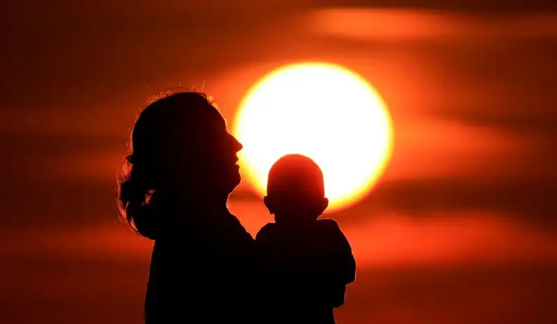 A mother and her baby enjoy the sunset on the beach in Calais