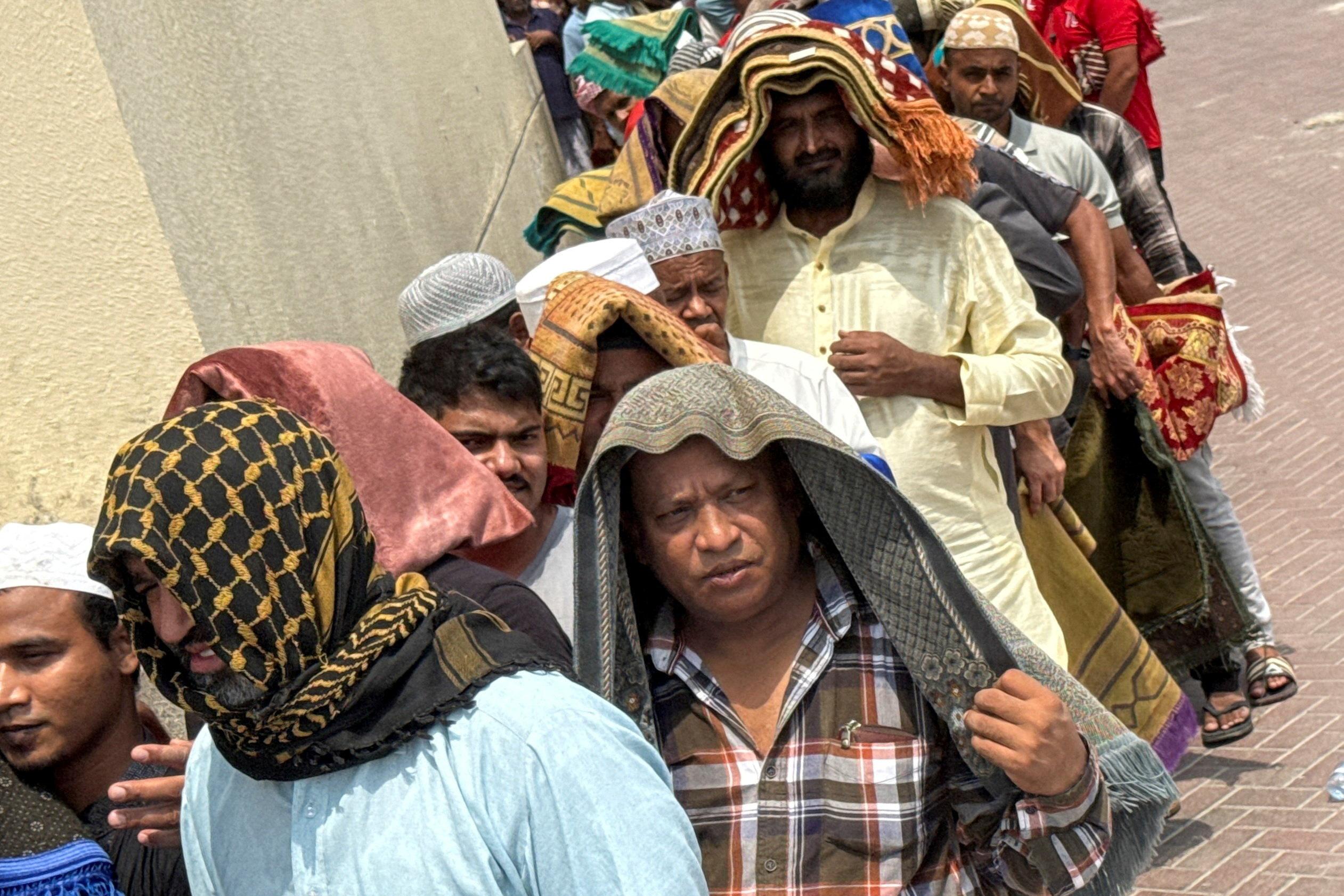 People cover their heads with prayer mats for shade following Friday prayers, during the summer heat in Dubai