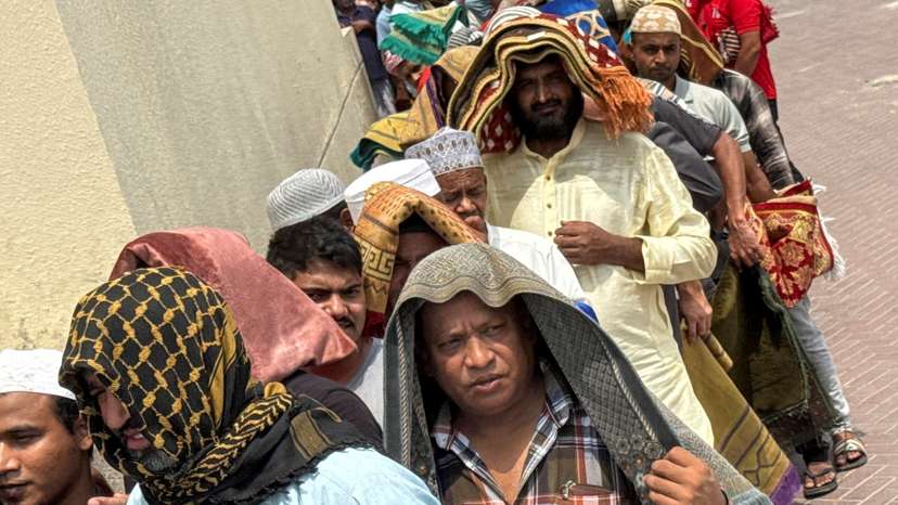 People cover their heads with prayer mats for shade following Friday prayers, during the summer heat in Dubai