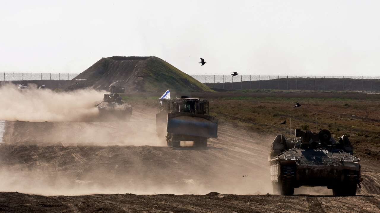 Military vehicles maneuvre near the Israel-Gaza border fence, in Israel