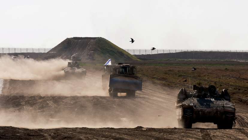 Military vehicles maneuvre near the Israel-Gaza border fence, in Israel