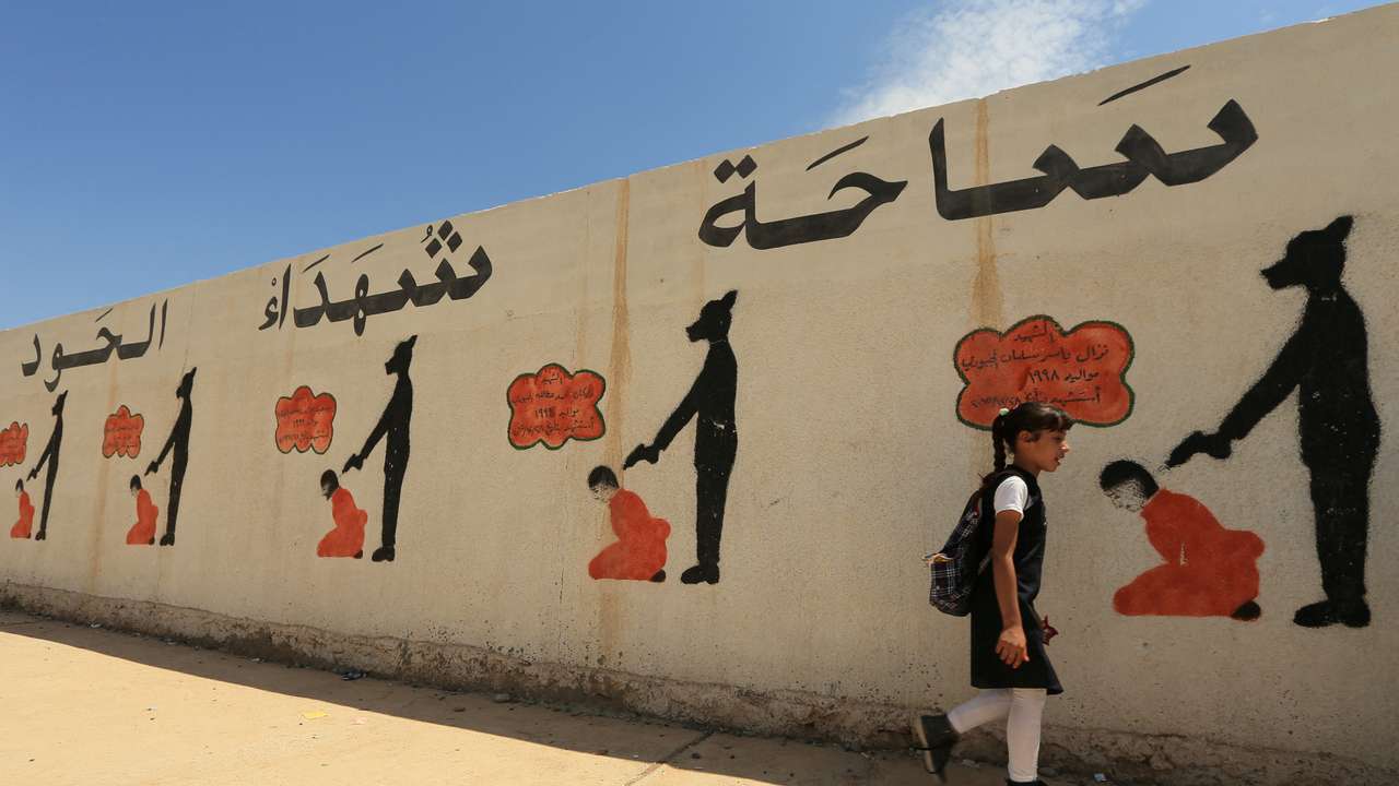 FILE PHOTO: An Iraqi student walks past a school wall covered with drawings showing how Islamic State militants executed their prisoners in Mosul