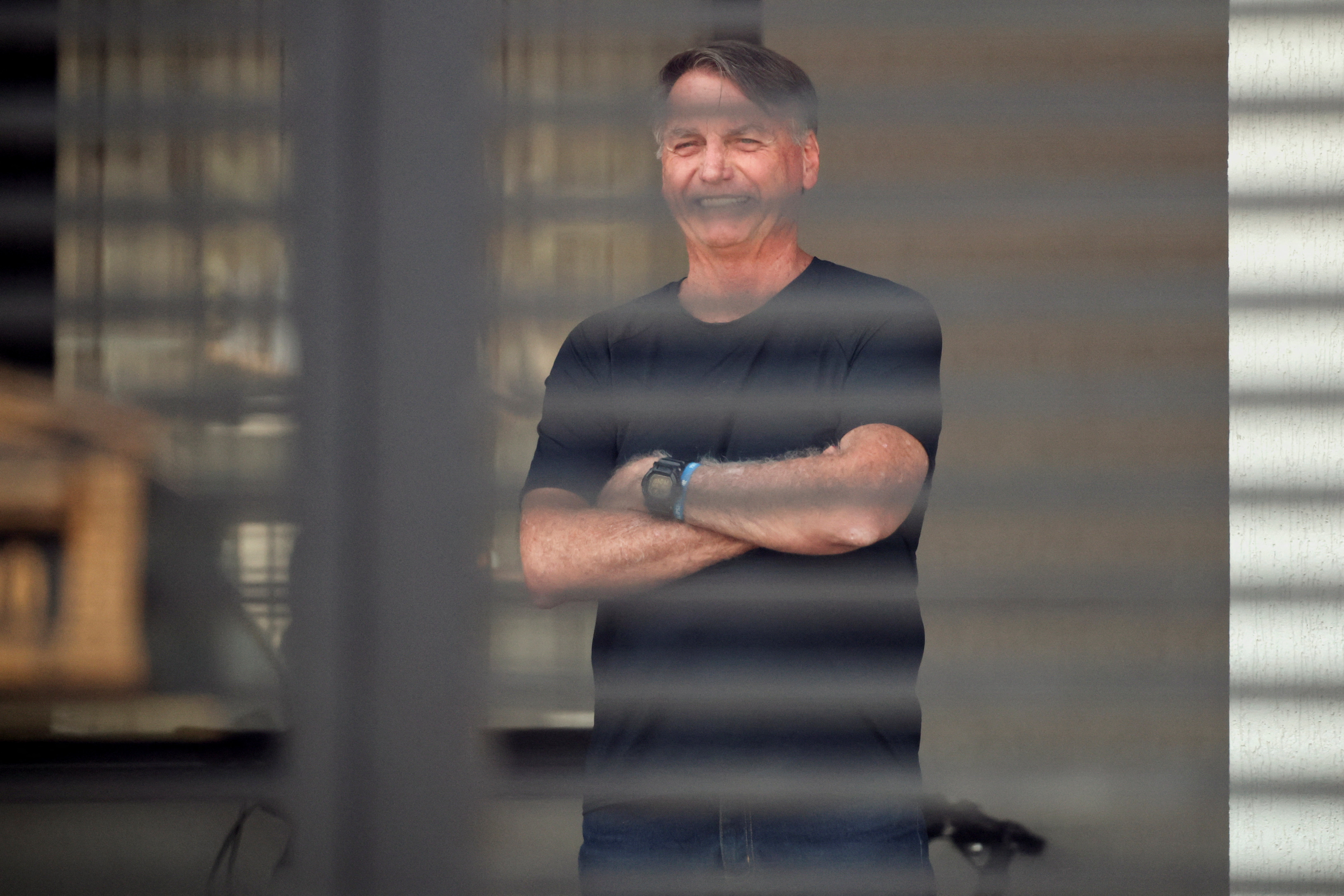 Brazil’s former President Jair Bolsonaro stands at his home while under house arrest, in Brasilia