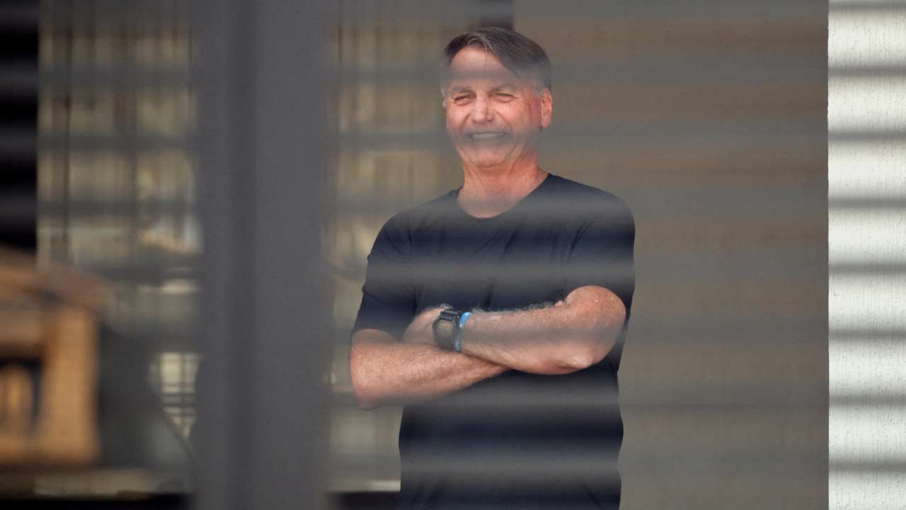 Brazil’s former President Jair Bolsonaro stands at his home while under house arrest, in Brasilia