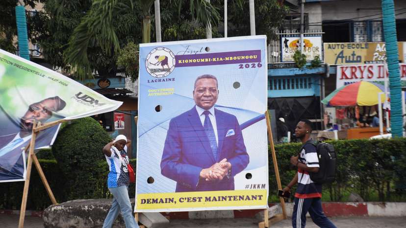 People walk past a campaign billboard of the presidential candidate, Joseph Kignoumbi Kia Mboungou, leader of La Chaine party, in Brazzaville