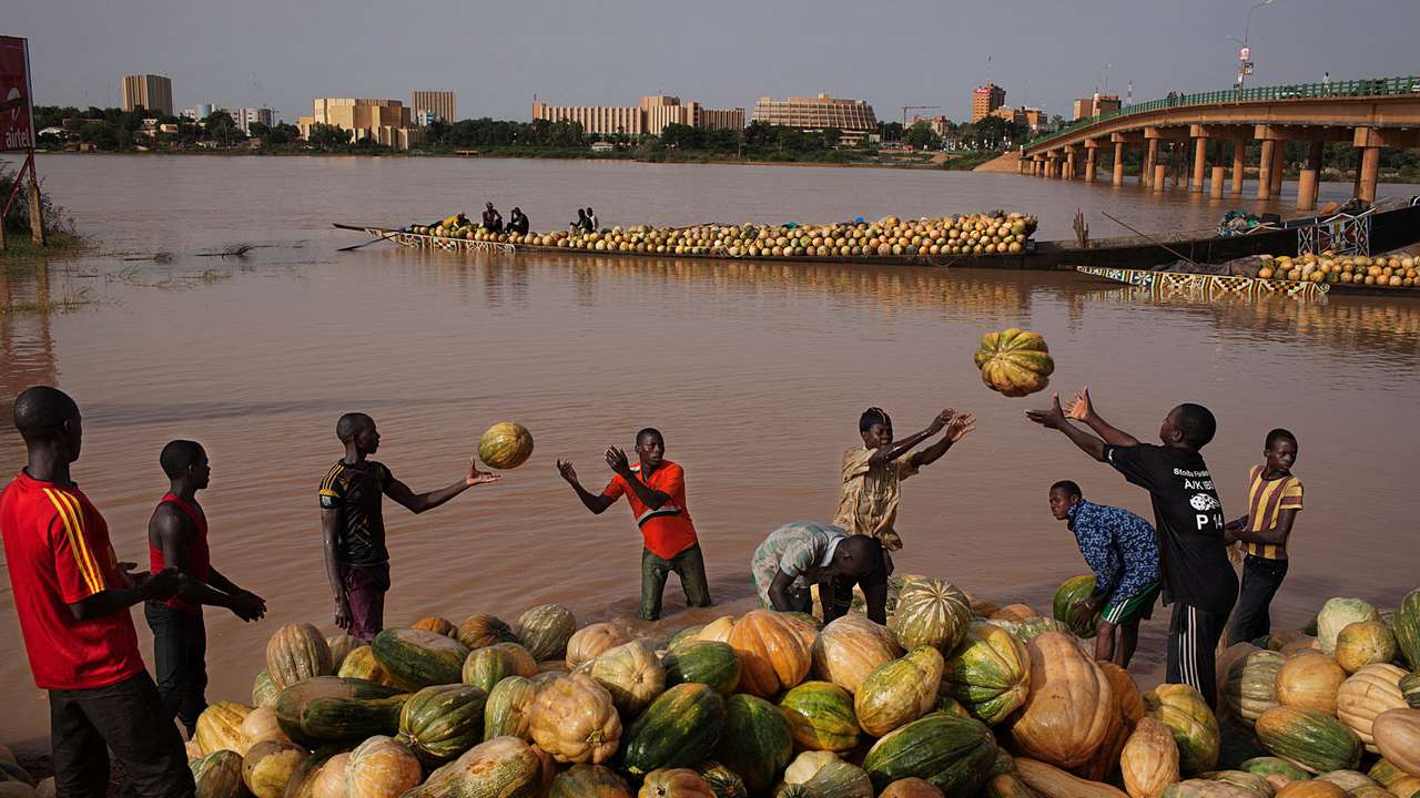 FILE PHOTO: Men toss squash onto the banks of the Niger River in Niamey