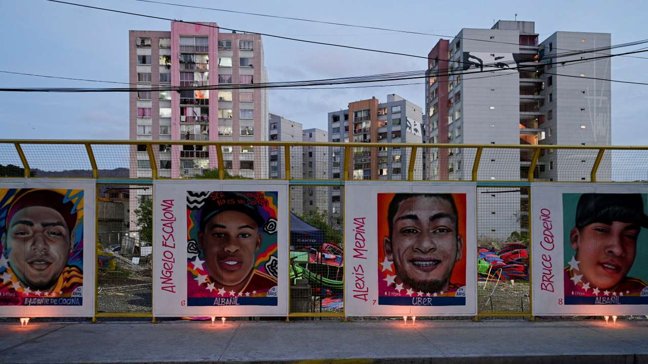 People light candles in front of a mural depicting Venezuelan migrants sent to El Salvador