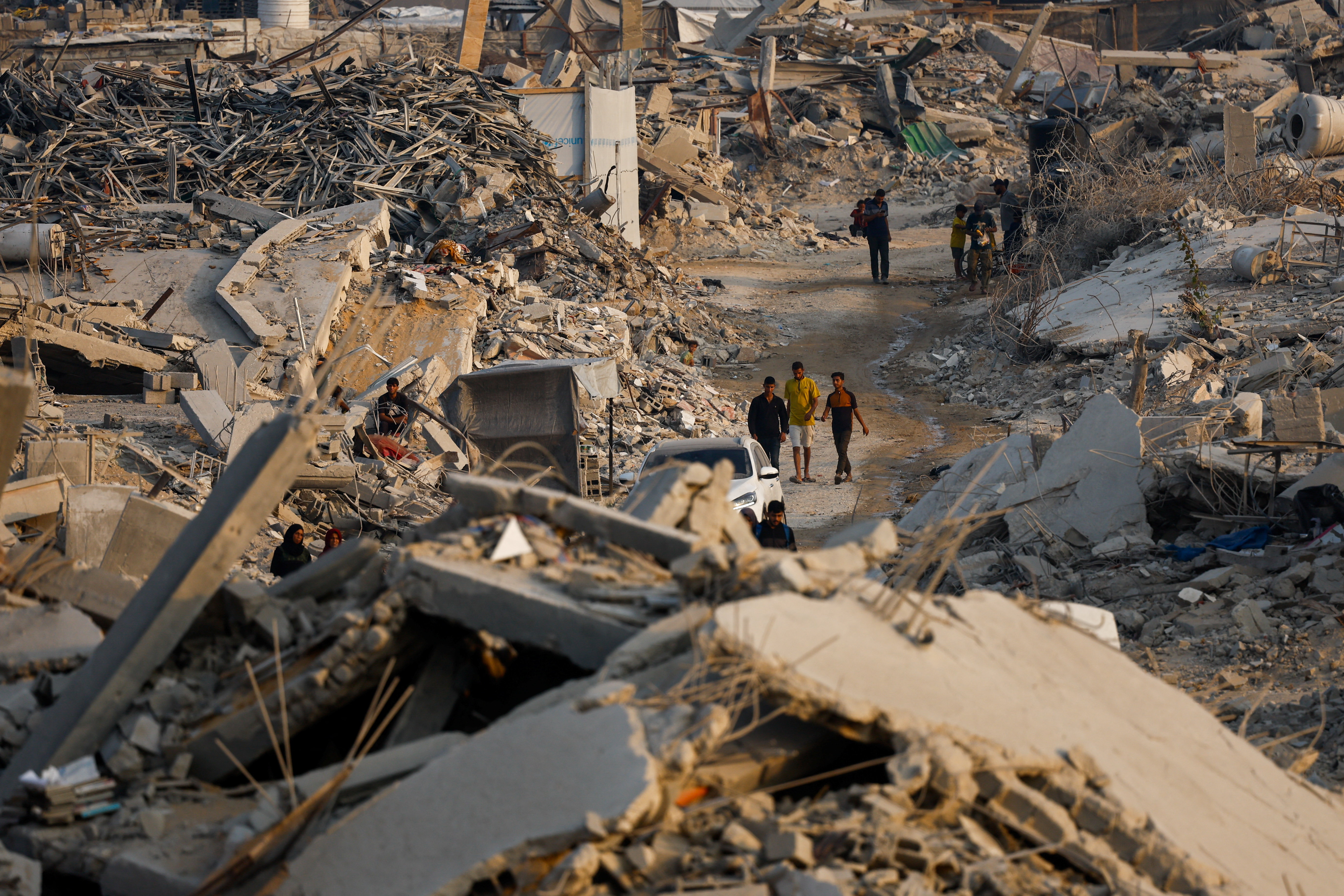 Palestinians walk past the rubble of destroyed buildings in Jabalia