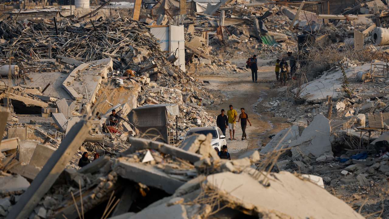Palestinians walk past the rubble of destroyed buildings in Jabalia